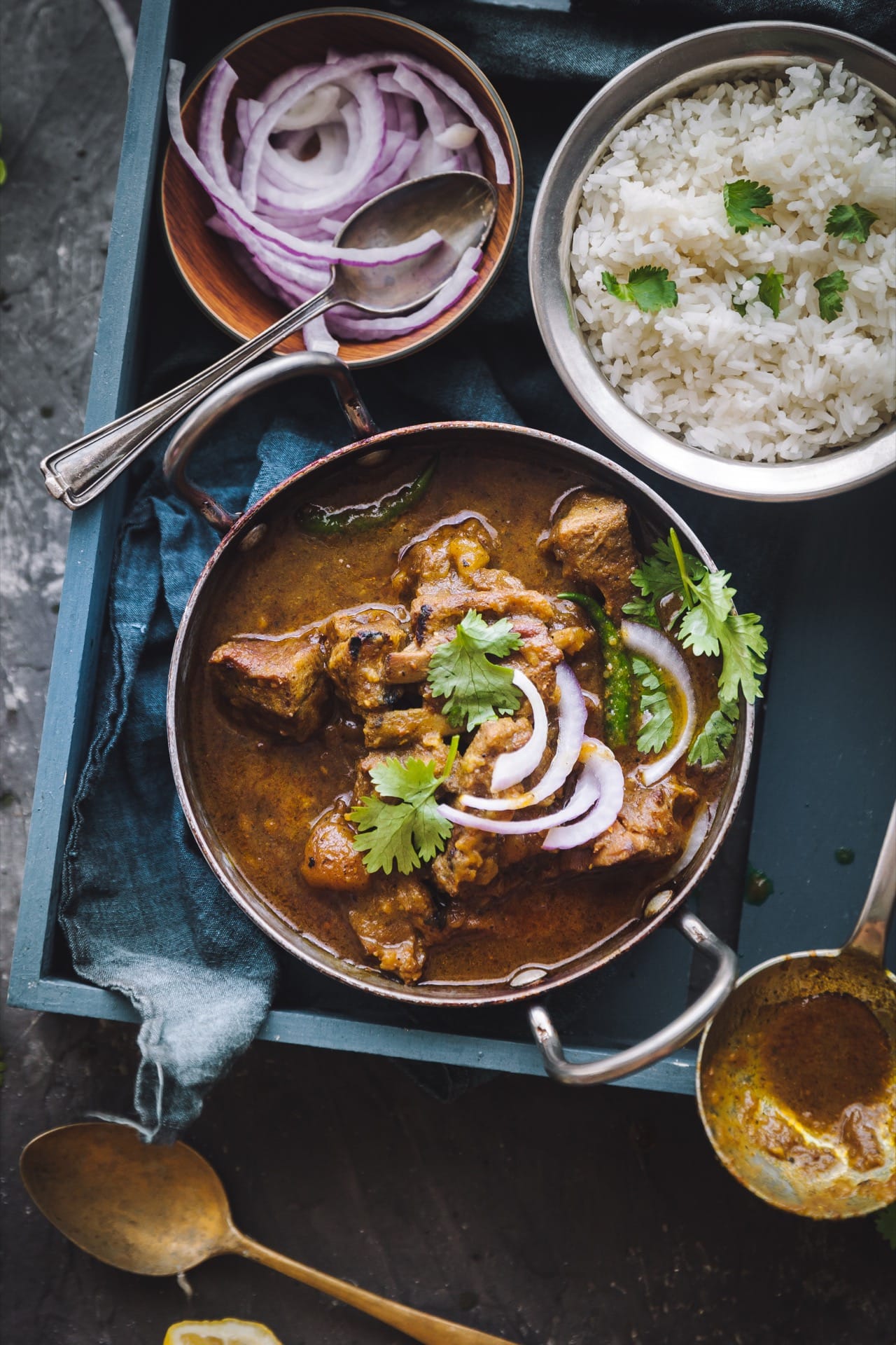 Over the top view of Sunday Mutton Curry in a bowl served with rice in a different bowl.