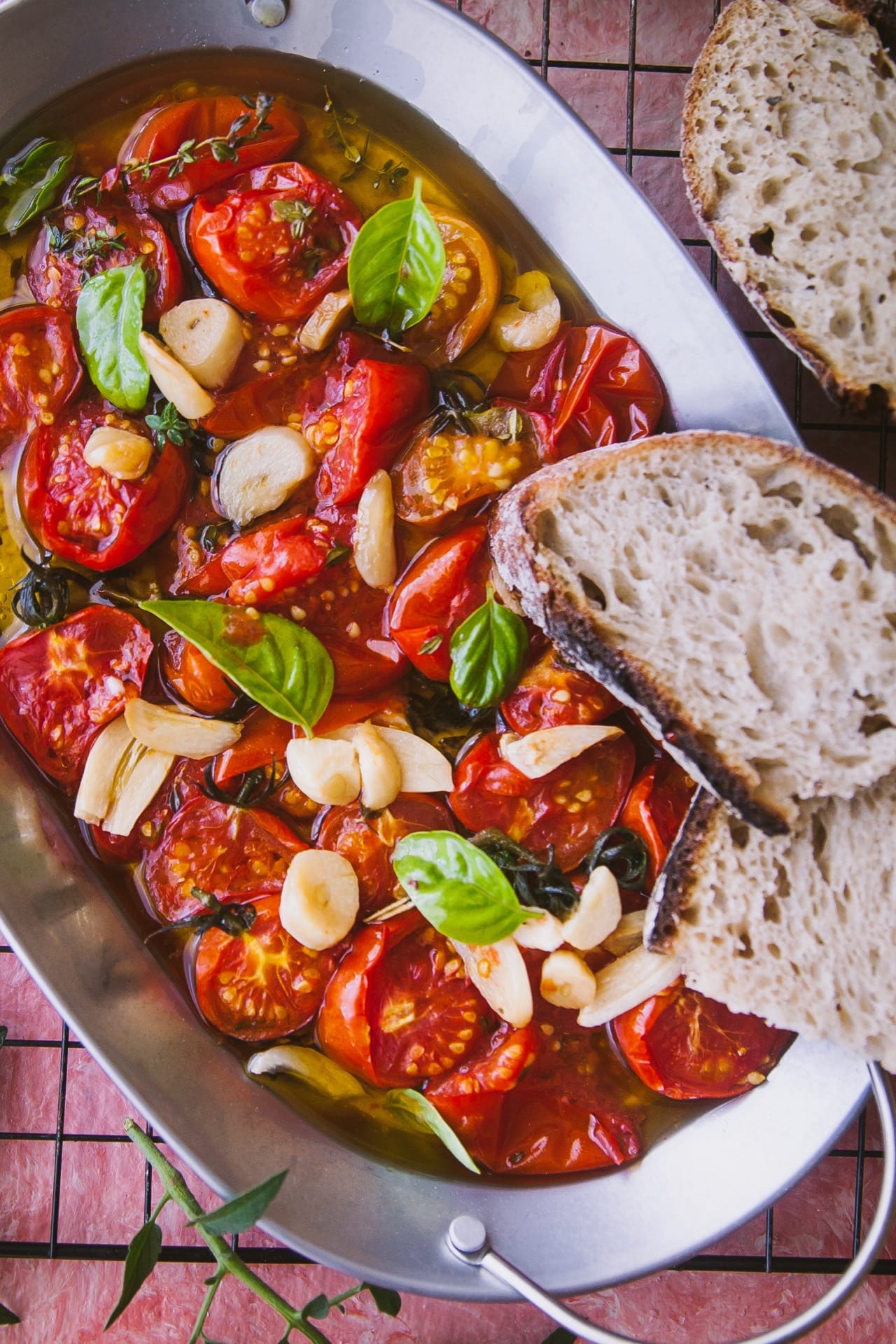 close up view of Tomato galic and basil on a tray with oil topped with two slices of bread and few bread slices are kept on the side
