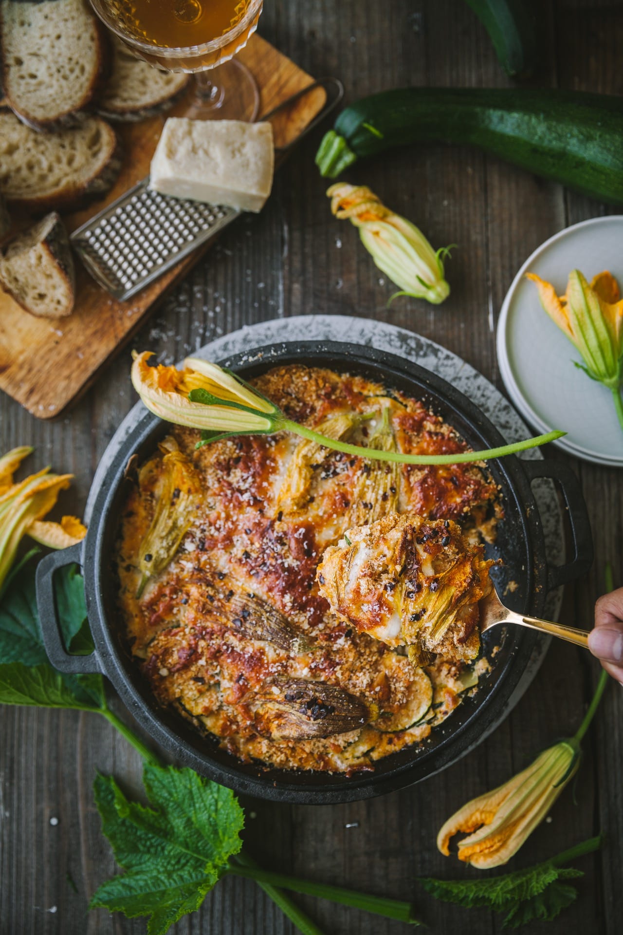 Zucchini gratin on a dish with cheese and zucchini blossoms every where