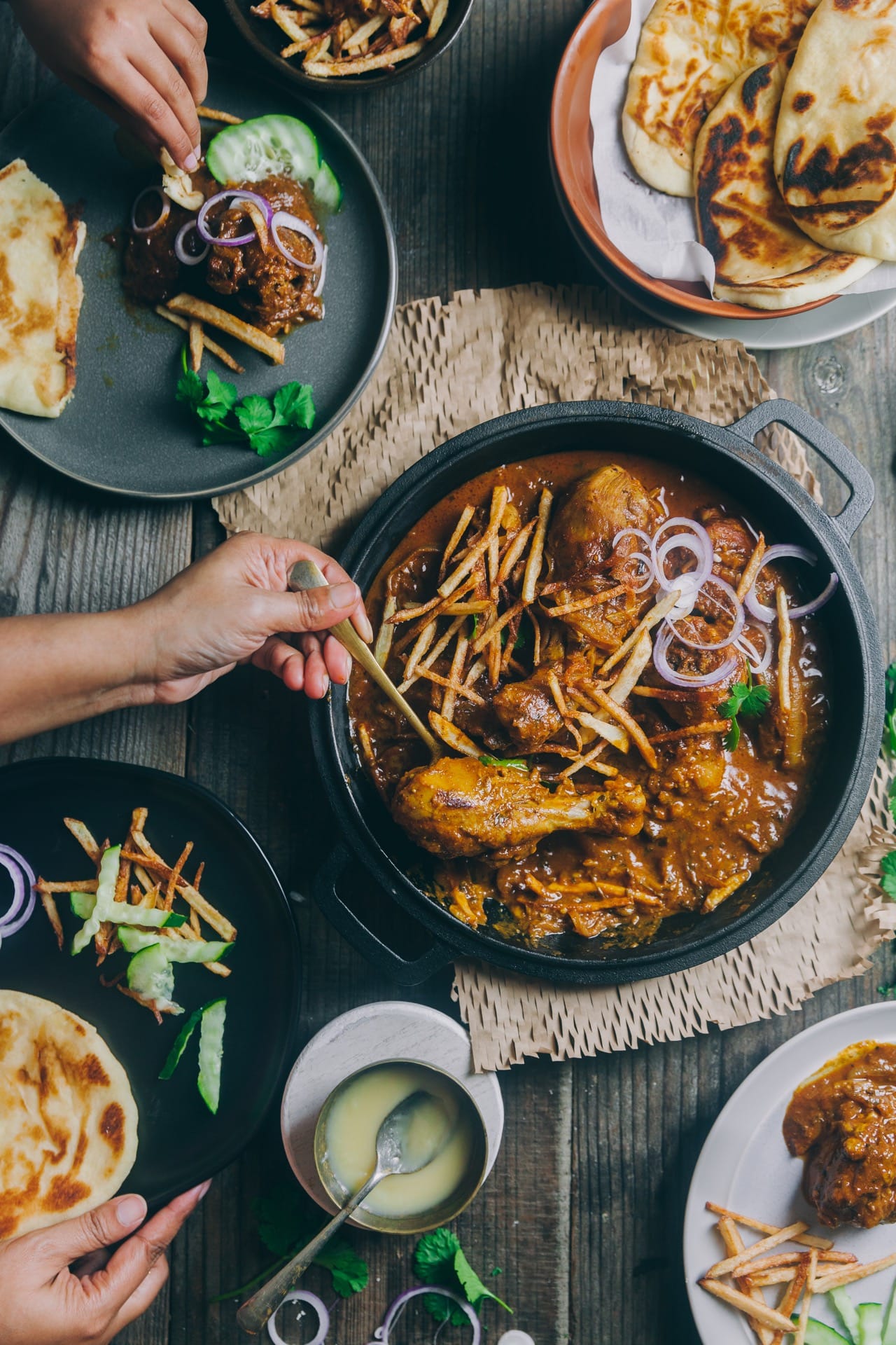 Flat lay view of Chicken Salli with plates across people eating