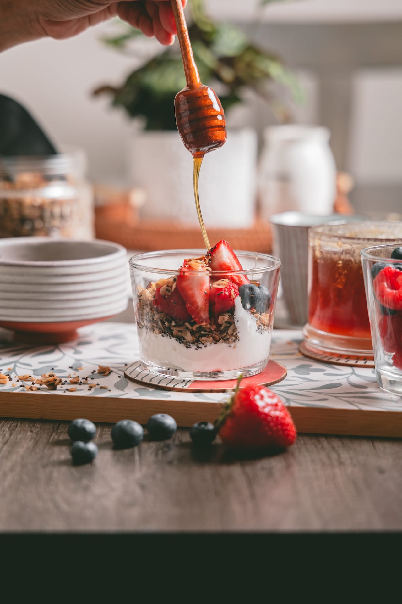 Drizzle honey on a bowl of yogurt granola and fruits. 